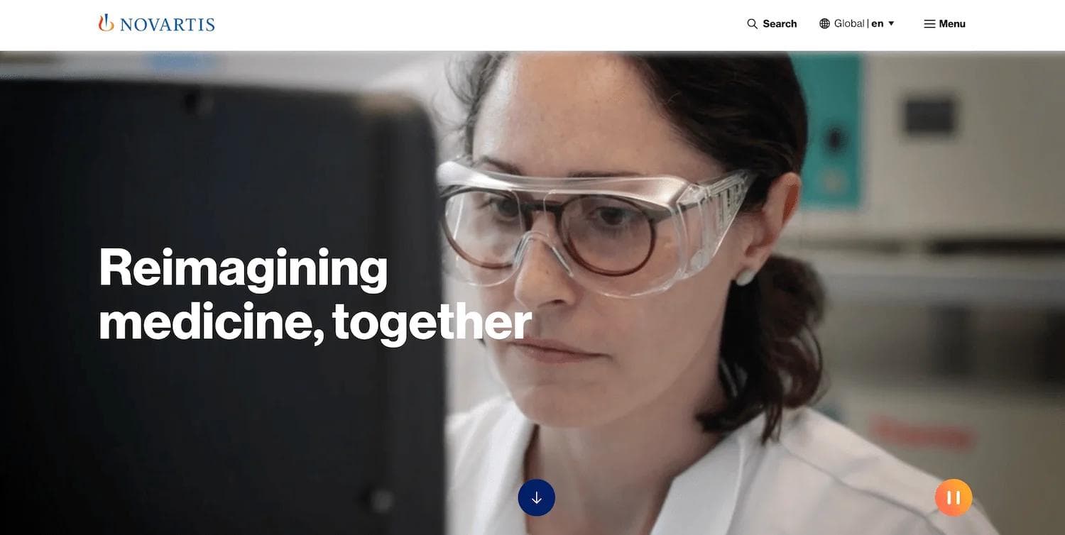 novartis homepage A woman in a lab coat and safety goggles focuses intently on a computer screen, with "Reimagining medicine, together" text.