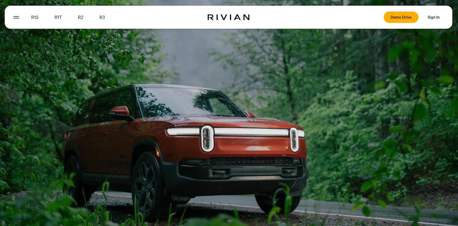 rivian web design A Rivian electric SUV parked on a forested road, surrounded by lush green foliage.