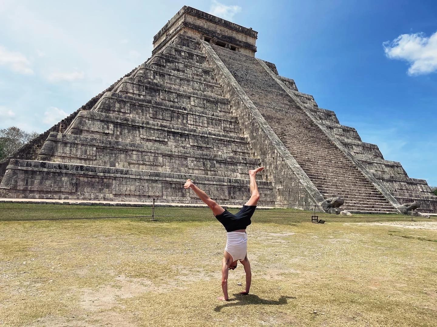 Seric Burns doing a handstand in front of a pyramid in Yucatan, Mexico.