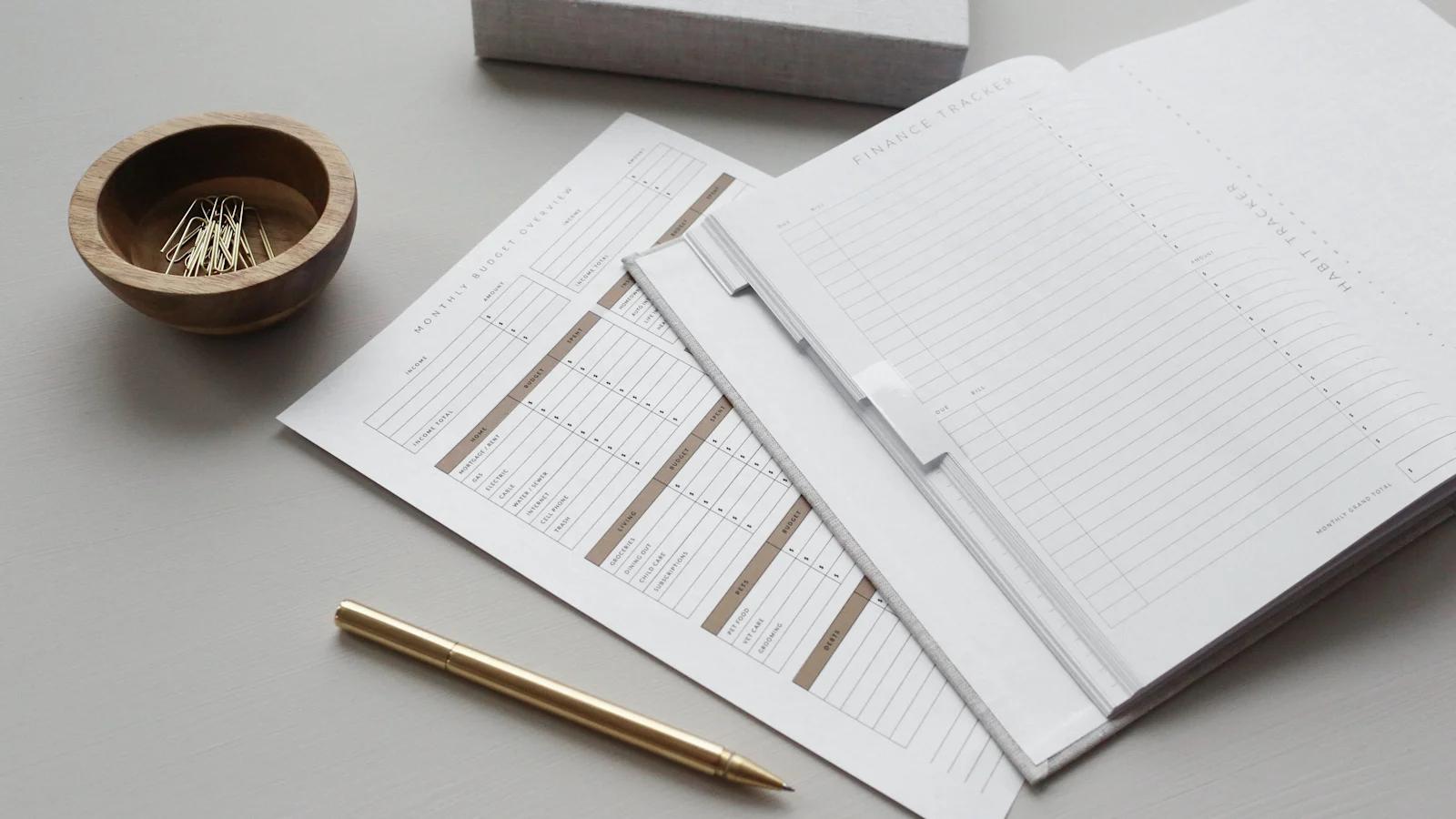 An image of a notebook with a finance sheet to the left of it.
