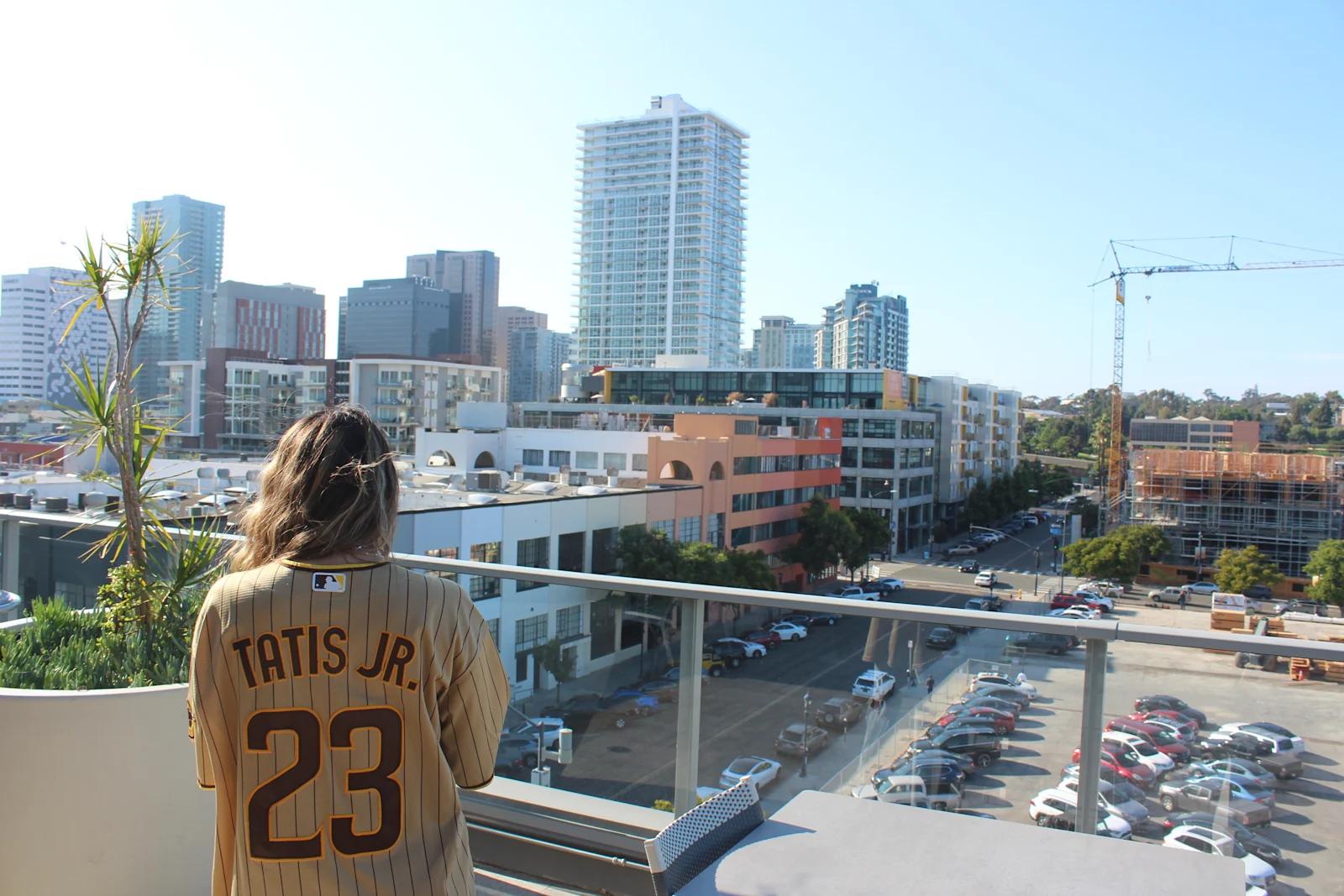 Natalie Qaqish wearing a brown San Diego Padres jersey standing on a rooftop in Downtown San Diego.